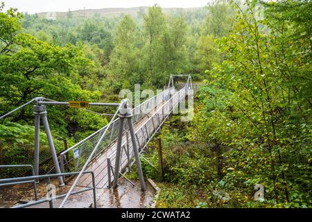 Ein eingefleischter Besucher trotzt dem heftigen Regen auf der Hängebrücke über die Corrieshalloch Gorge, Wester Ross, Highland Region, Schottland, Großbritannien Stockfoto