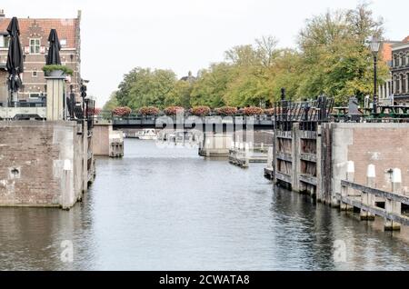 Gorinchem, Niederlande, 23. September 2020: Blick entlang des Linge Flusses, gesäumt von Bäumen, und überquert von einer Brücke mit Blumen geschmückt Stockfoto