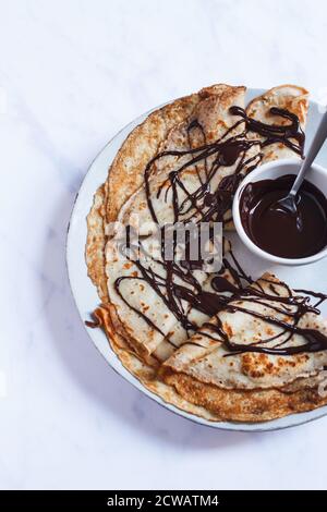 Stapel von Französisch Crepes in Dreiecken gefaltet auf einem großen Teller mit einem Niesel von dunkler Schokoladensauce. Stockfoto