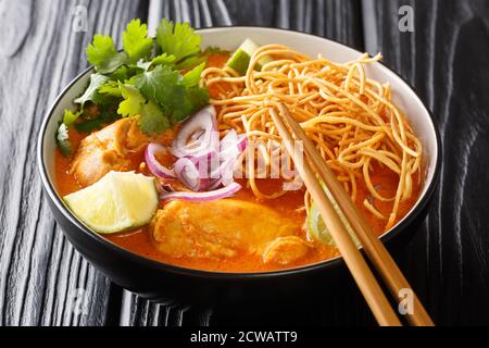 Huhn khao soi thai Kokosnuss Curry Nudelsuppe Nahaufnahme in der Schüssel auf dem Tisch. Horizontal Stockfoto