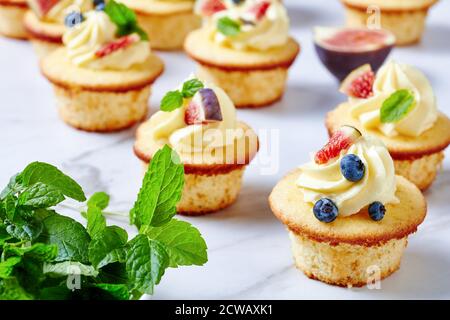 Köstliche Cupcakes mit Buttercreme und frischen Beeren und Minze auf einem Marmortisch, Landschaftsansicht von oben, Nahaufnahme Stockfoto