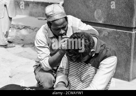 Ein Mann reinigt Kundenohr, Ohrenschmalz für Geld auf vielbefahrenen Straße in chandani chowk, alt delhi, indien. Stockfoto