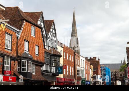 Gebäude in der High Street Salisbury, mit der Kathedrale Spire drohende große im Hintergrund, Salisbury, England. Stockfoto