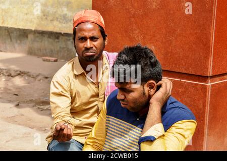 Ein Mann zeigt und Reinigung Kundenohr, Ohrenschmalz für Geld auf verkehrsreichen Straße in chandani chowk, alt delhi, indien. Stockfoto