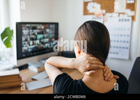 Junge Frau mit Nackenschmerzen nach langen Arbeitszeiten im Heimbüro. Lösen Sie die Spannung im Nacken. Stockfoto