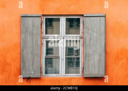 Alte hölzerne Fensterläden eines europäischen Hauses mit orange bemalter Fassade, vintage Hintergrund. Stockfoto