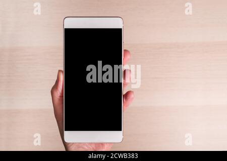 Hand hält Smartphone mit leerem Bildschirm isoliert auf Holzhintergrund Stockfoto