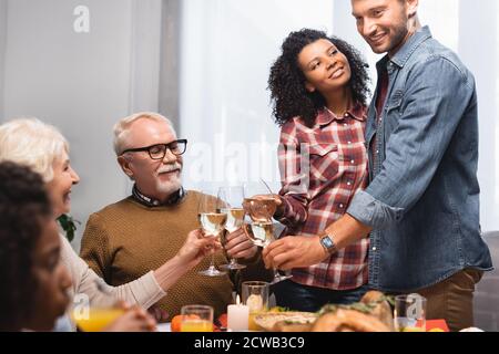 Selektiver Fokus der multikulturellen Familie klirrende Gläser Weißwein Während des Dankes-Tages Stockfoto