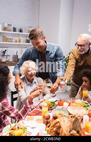 Selektiver Fokus der multiethnischen Familie Klickern mit Wein während der Danksagung Feiern Stockfoto