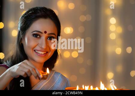 Frau lächelt mit einem Diya in der Hand Stockfoto