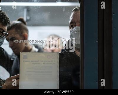 Moskau. Russland. September 28, 2020. Ein Mann in einem U-Bahn-Auto schaut durch die Fensterscheibe. Der Beifahrer hat eine medizinische Schutzmaske im Gesicht. Der Stockfoto