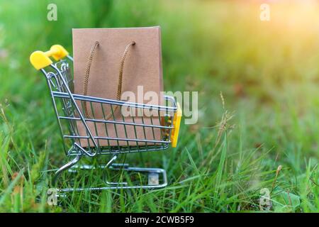 Papiertüte neben dem Supermarkt-Trolley. Das Konzept ist der Kauf von umweltfreundlichen Produkten. Recycelte Waren. Stockfoto