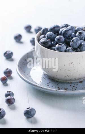 Blaue Keramik Tasse Heidelbeeren mit Untertasse blau Holztisch gesichtet. Rustikalen Stil. Stockfoto