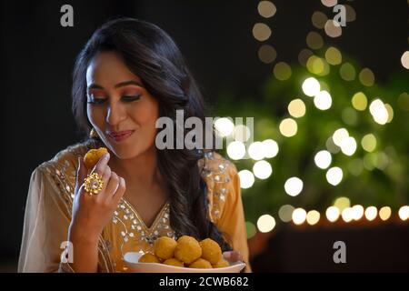 Frau, die nach einem Bissen einen Ladoo ansieht Stockfoto