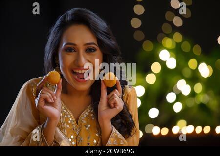 Frau lächelt mit ladoos in den Händen bei der Gelegenheit Von Diwali Stockfoto