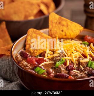 Nahaufnahme einer Schüssel Chili con Carne mit Cheddar-Käse Und Nacho-Chips Stockfoto