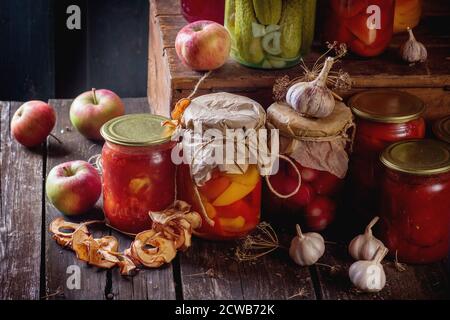 Sammlung Set von vielen hausgemachten Gläsern mit Konserven (Gurken, Tomaten, Paprika), mit Knoblauch und frischen und getrockneten Äpfeln. Über altem Holz Stockfoto