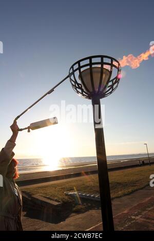 Prestwick, Ayrshire, Schottland Großbritannien 05. Juni 2012 Beleuchtung eines Leuchtfeuers am Prestwick Beach zur Feier der Olympischen Spiele 2012 mit der Isle of Arran und dem Firth of Clyde Ground ging die Sonne unter, so dass es einen Lichtreflexe vom sunlight.beacons. Oder Feuerfeuer, waren Feuer, die angezündet wurden, um die lokalen Menschen vor dem Herannahen eines Feindes zu warnen. Sie lagen auf hohen Hügeln, in der Regel als Teil eines defensiven Signalsystems oder einer Kette, die sich von der Küste bis ins Landesinnere erstreckte. Das Signal wurde durch Rauch am Tag und Licht in der Nacht gegeben. Stockfoto