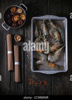 Zutaten für asiatische Abendessen gekocht, Soba-nudeln, getränkt Shiitake Pilze und Garnelen über alte Holz- Hintergrund mit Salz und Chili Flak Stockfoto