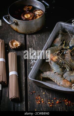 Zutaten für asiatische Abendessen gekocht, Soba-nudeln, getränkt Shiitake Pilze und Garnelen über alte Holz- Hintergrund mit Salz und Chili Flak Stockfoto