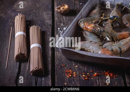 Zutaten für asiatische Abendessen gekocht, Soba-nudeln, getränkt Shiitake Pilze und Garnelen über alte Holz- Hintergrund mit Salz und Chili Flak Stockfoto