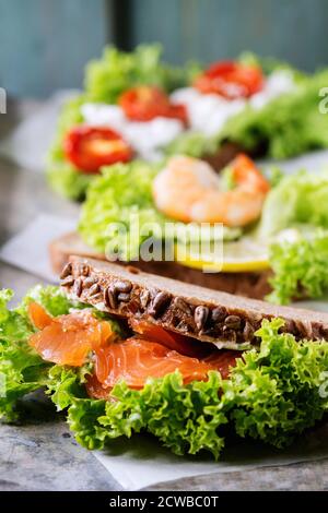 Satz von Sandwiches mit Vollkornbrot, frischem Salat, Feta, Kirschtomaten, Garnelen und gesalzenen Lachs auf alte Zinn Hintergrund. Stockfoto