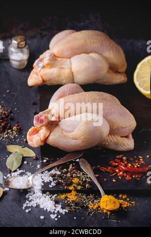 Zwei Raw Mini Huhn mit Meer-Salz und verschiedenen Gewürzen über Schiefer Tafel Stockfoto