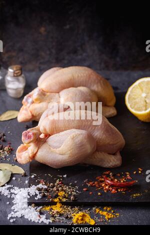 Zwei Raw Mini Huhn mit Meer-Salz und verschiedenen Gewürzen über Schiefer Tafel Stockfoto