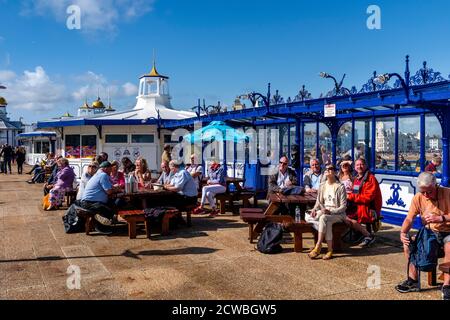 Leute, die vor EINEM Cafe am Eastbourne Pier sitzen und die Eastbourne Airshow, Eastbourne, East Sussex, Großbritannien, beobachten Stockfoto