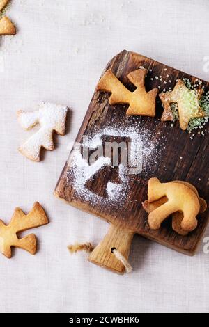 Shortbread Weihnachtsplätzchen für Tassen in Zuckerpulver und kleine Schneidebrett über Tisch mit weißer Tischdecke. Draufsicht. Form wie Weihnachtsbaum, sta Stockfoto