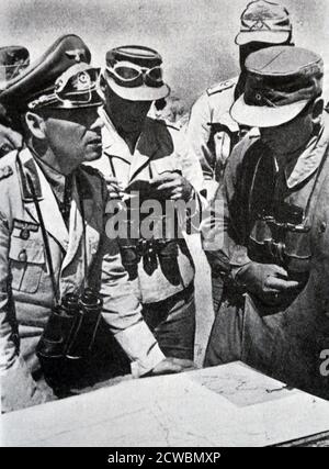 Schwarz-Weiß-Fotografie des Zweiten Weltkriegs (1939-1945); General Erwin Rommel (1891-1944), Kommandant des Afrikanischen Korps, steht über einer Karte, die seine Offiziere anweist. Stockfoto
