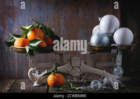 Mandarinen mit Blättern und weißen Weihnachtsdekorationen auf Vintage-Schuppen über Holztisch mit dunklem Metall Hintergrund. Dunkler rustikaler Stil. Stockfoto