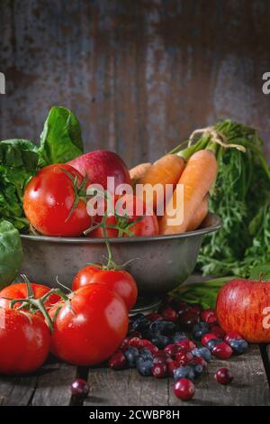 Auswahl an frischem Obst, Gemüse und Beeren. Bündel Karotten, Spinat, Tomaten und rote Äpfel in vintage Metall Schüssel, Heidelbeeren und Cranberr Stockfoto