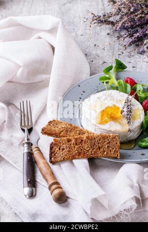 Blaupunktrochen Platte mit frischem Ziegenkäse mit Honig, Honig, Lavendel, Himbeeren serviert, grüner Salat und Vollkorn Toast auf weißem Textil über Stockfoto