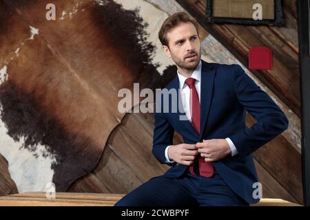 Selbstbewusster Geschäftsmann, der in einem Coffeeshop sitzt und den Mantel anpasst Stockfoto