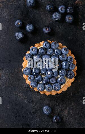 Zitronen-Törtchen mit frischen Heidelbeeren auf schwarzem Hintergrund. Ansicht von oben. Mit Platz für text Stockfoto