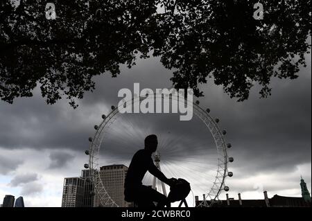 Ein Mann radelt am London Eye am Ufer in London vorbei. Stockfoto