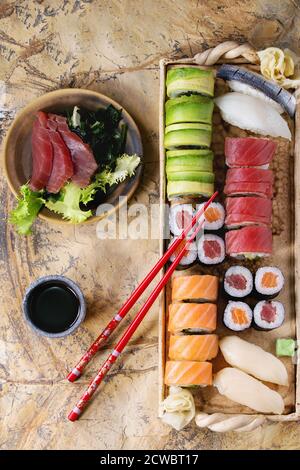 Sushi set Nigiri, Sashimi und Rollen auf Ton Platte serviert mit Stäbchen und Soja-Sauce auf der Steinoberfläche. Flach zu legen. Stockfoto