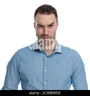 Angewiderte Casual Mann runzelte beim Tragen von blauen Hemd, auf weißem Studio Hintergrund stehen Stockfoto