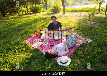 Gitarre spielen im Park glückliches Paar Stockfoto