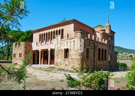 Das Schulgebäude in der Colonia Guell in Santa Coloma de Cervello, Spanien, das im Hintergrund an das Gebäude Casa del Mestre angeschlossen ist, wurde in beiden Gebäuden gebaut Stockfoto