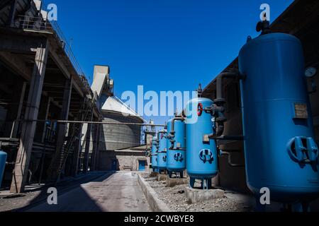 Mynaral/Kasachstan - April 23 2012: Zementanlage von Jambyl. Wasseraufbereitungsstation. Blaue Wasserfiltertanks, roter Ventilanker und Rohre. Runde Konz Stockfoto