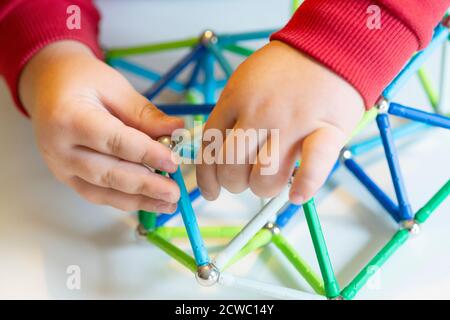 Hand hält Magnet Spielzeugstangen und magnetische Bälle Stockfoto