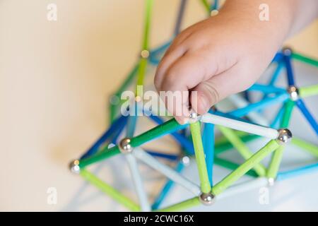 Hand hält Magnet Spielzeugstangen und magnetische Bälle Stockfoto