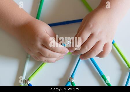 Hand hält Magnet Spielzeugstangen und magnetische Bälle Stockfoto