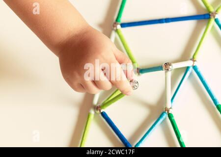 Hand hält Magnet Spielzeugstangen und magnetische Bälle Stockfoto