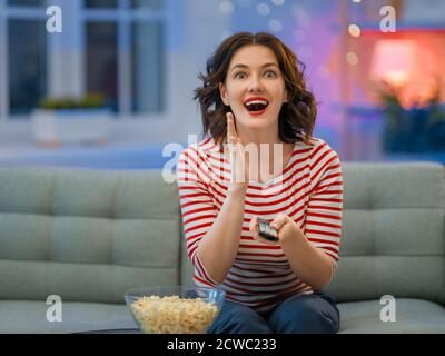 Junge Frau beim Fernsehen, Filme mit Popcorn am Abend. Mädchen verbringt Zeit zu Hause. Stockfoto