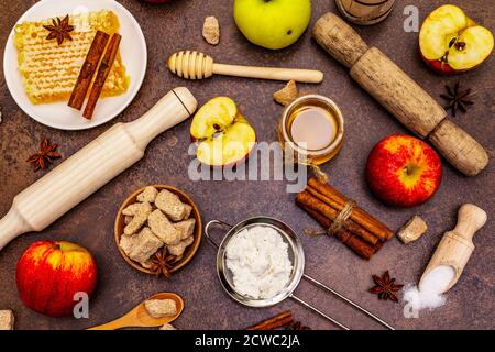 Apfelkuchen-Backkonzept. Reife Äpfel, frischer Honig und gesunde Zutaten. Steinbeton Hintergrund Stockfoto