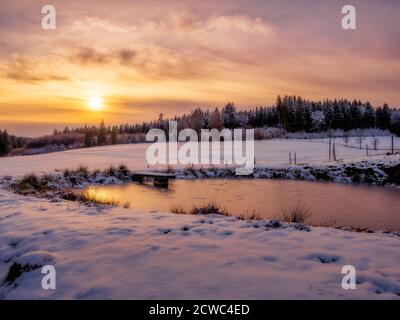 Wunderschöne Winterlandschaft mit gefrorenem See und Schnee während des Sonnenuntergangs. Stockfoto