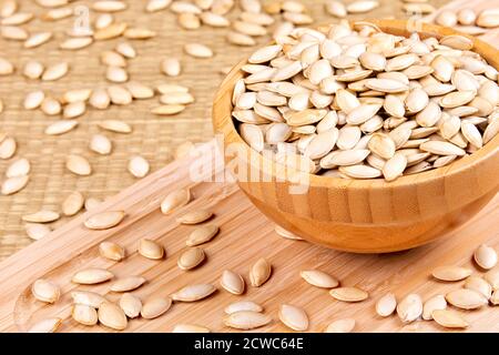 Schüssel voll mit leckeren Kürbiskernen, ein gesunder Snack auf einem hölzernen Hintergrund Stockfoto